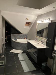 Un baño con dos lavabos, una bañera y un espejo. en Maison Corneille proche de Lille, en Hem