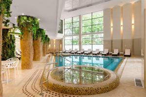a large swimming pool with chairs and a table and a building at Aqua Perla Boutique Hotel in Chişinău