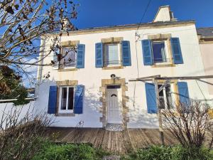 a white house with blue shutters on it at 729-Maison de pecheur a 150m de la plage in Plouhinec