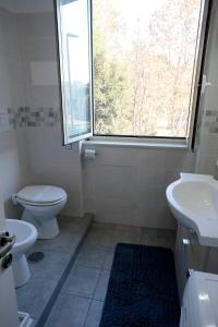 a bathroom with a toilet and a sink and a window at Metro&Mare House in Lido di Ostia +16 photos