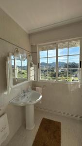 a white bathroom with a sink and two windows at Casa Afouteza en Aldán in Piñeiro