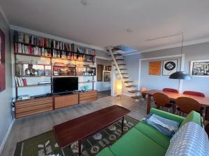 Homely flat with amazing views في ريكيافيك: غرفة معيشة بها أريكة خضراء وتلفزيون