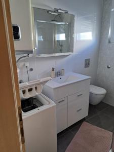 biała łazienka z umywalką i toaletą w obiekcie Apartman Lozančić w mieście Vir