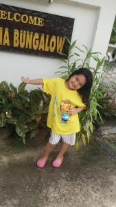 a young girl standing in front of a building at Wattana Bungalow in Nai Yang Beach
