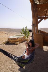 una donna sdraiata su un'amaca con un bambino di Desert Days mud cabin's Resort a Zuqim