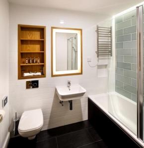 Un baño con lavabo, inodoro y bañera. en Downing College, en Cambridge