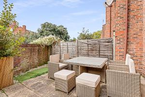 a patio with a table and chairs and a brick wall at Beautiful Three-Bedroom House in Richmond in Richmond upon Thames