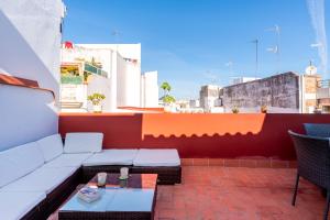 a patio with a couch and a table on a roof at Holi-Rent Penthouse Peñuelas in Seville