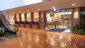 a lobby with a wooden floor and escalators in a building at Toyoko Inn Akita-eki Higashi-guchi in Akita +34 photos