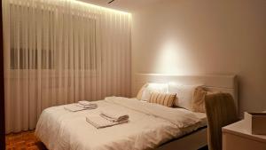a white bed with two pairs of shoes on it at Aparte - Standard in Pristina