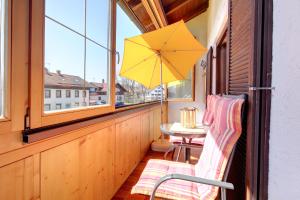 a balcony with a table and a yellow umbrella at Haus Schmölz Ferienwohnung Allgäu in Hopferau