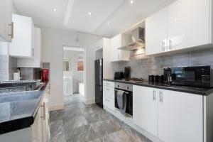 Thornaby on TeesにあるClassic 4-Bedroom Retreat close to Infinity Bridgeの白いキャビネットと黒い冷蔵庫のあるキッチン