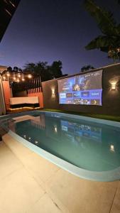 una piscina notturna con tv sullo sfondo di Duda House com piscina aquecida a Penha