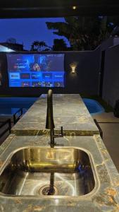 un lavello con televisore sullo sfondo di Duda House com piscina aquecida a Penha