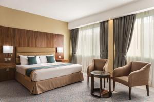 a hotel room with a bed and a chair at Howard Johnson by Wyndham Abu Dhabi Downtown in Abu Dhabi