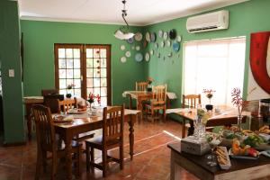 a dining room with green walls and wooden tables and chairs at Daisy Country Lodge in Springbok