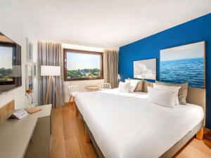 a hotel room with a large white bed and blue walls at Novotel Gdańsk Marina in Gdańsk