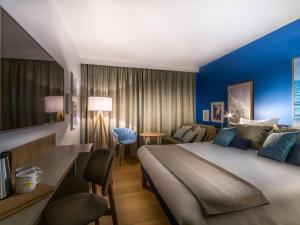 a hotel room with a large bed and a couch at Novotel Gdańsk Marina in Gdańsk