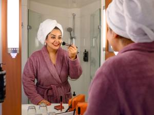 a woman brushing her teeth in front of a mirror at ibis Stuttgart Airport Messe in Leinfelden-Echterdingen