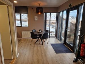 a dining room with a table and chairs and windows at Black Beach Farm in Vík