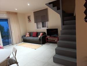 a living room with a couch and a staircase at Altheas Maisonettes in Xylokastro