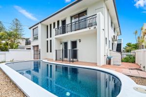 una villa con piscina frente a una casa en Perfect Waterfront Escape in Surfers Paradise, en Gold Coast