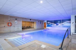 a swimming pool in a building with a painting on the wall at Chalet Alaska Val thorens 130 m2 - Pied des pistes de samedi à samedi in Val Thorens
