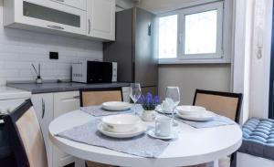 una cocina con una mesa blanca con platos y copas de vino en On Arbat the Center of Almaty, en Almaty