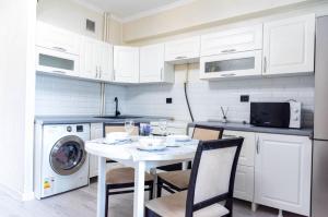 Una cocina blanca con una mesa y sillas y una lavadora. en On Arbat the Center of Almaty, en Almaty