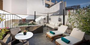 a balcony with chairs and a couch and a table at Hotel Boutique Corral del Rey in Seville