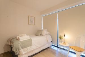 Un dormitorio blanco con una cama y una ventana. en Elegant 2BR Experience Las Condes in Style, en Santiago