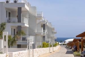 a white apartment building with balconies on a street at Color Dream Residence in Monopoli