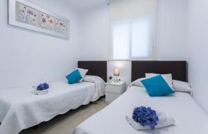 two beds in a room with blue pillows on them at El Balneario in Cádiz +7 photos