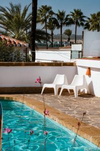 a pool with two white chairs and palm trees at Los Bungalows Del Arenal in Jávea +80 photos