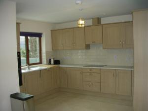 an empty kitchen with wooden cabinets and a window at 18 Carraig Naofa in Bantry