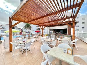 un restaurante con mesas y sillas blancas y una pérgola de madera en Bungalow Tinerfe Garden, en Adeje