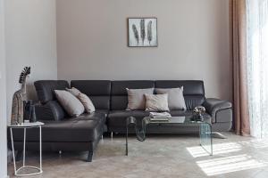 un salon avec un canapé noir et une table dans l'établissement GREEN HILL 2 Apartmani with POOL, à Gornji Orahovac 21 autres photos