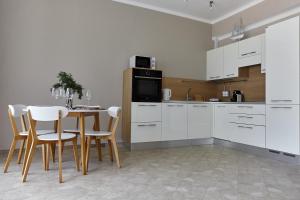 une cuisine avec des armoires blanches et une table et des chaises dans l'établissement GREEN HILL 2 Apartmani with POOL, à Gornji Orahovac