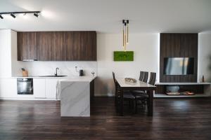 a kitchen with white counters and a table with a dining room at OLI Apartmán in Stará Lesná