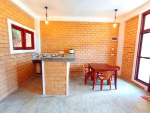 a dining room with a table and a brick wall at CDR Eco Home in Weligama