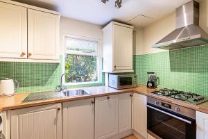 a kitchen with white cabinets and a sink and a stove at Cosy Flat in Battersea Park in London