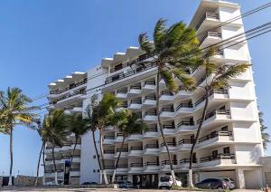 biały budynek z palmami przed nim w obiekcie JATIÚCA SUITES RESORT - Flat VISTA MAR w mieście Maceió
