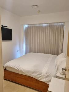 a bedroom with a white bed with a window at חדר שינה וסלון ומרפסת נוף לים in Herzliyya B