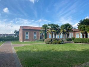 a brick building with palm trees in a park at La casetta al parco in Ponte San Nicolo