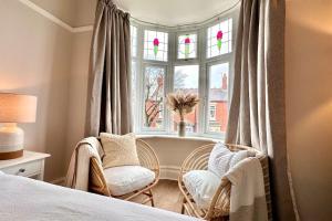 a bedroom with two chairs in front of a window at Stunning Coastal Retreat Whitley Bay Sleeps 9 in Whitley Bay