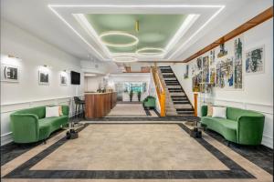 ケチケメートにあるAranyhomok Business-City-Wellness Hotelの緑の椅子と階段のあるロビー