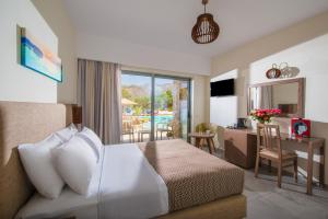 a hotel room with a bed and a desk with a table at South Coast Hotel in Makry Gialos