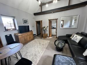 a living room with a black couch and a table at Holmleigh Annexe in Tamworth