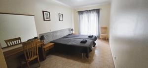 a bedroom with a bed and a desk and a window at Open Space - Albufeira in Albufeira