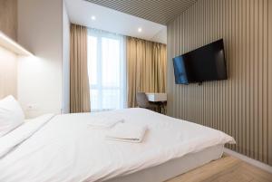 a bedroom with a white bed and a flat screen tv at Nyvky Like Home - Файна Таун із сезонним басейном - Кв 58 in Kyiv +35 photos